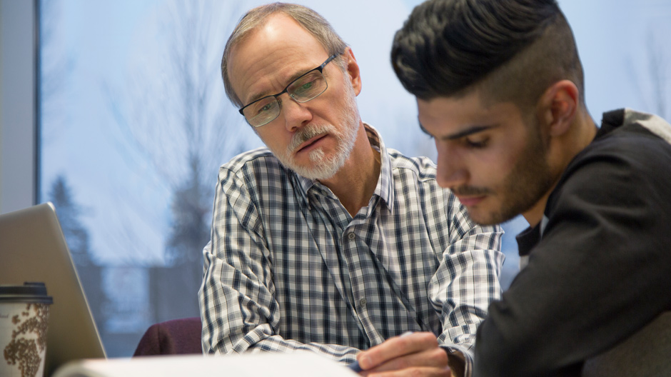 Professor and college student looking at book